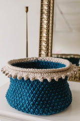 Teal basket with cream trim in front of mirror thumbnail