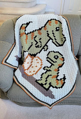 Close up of crochet afghan with t-rex family laying on couch. thumbnail