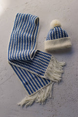 Flat lay of striped blue & white scarf and matching hat with white brim and pompom. thumbnail
