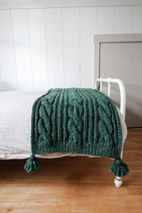 Green ribbed and cabled throw with large tassels at each corner. thumbnail