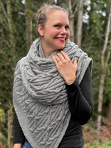 Woman wearing grey cabled shawl wrapped around neck. thumbnail