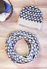 Crochet beanie and matching infinity scarf, coiled twice, on wooden backdrop. thumbnail