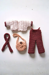 Flat lay of crochet doll clothes - jumpsuit, jacket, scarf, and bag. thumbnail