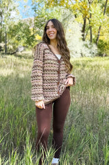 Woman stands in tall grass wearing crochet cardigan buttoned up the front. thumbnail