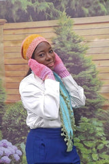 Woman in white top and blue skirt wears crochet beanie, matching mittens, and scarf with bobbled edge and tassels. thumbnail