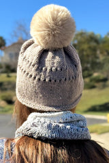 Back view of tan knit beanie with two rows of eyelets and coordinating faux fur pom pom. thumbnail