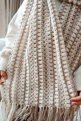 Woman holds scarf toward camera, showing fringe. thumbnail