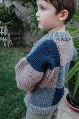 Side view of cardigan, worn by young boy standing in a grassy yard. thumbnail