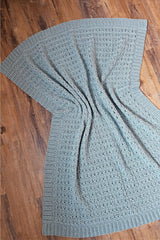 Full view of crochet textured blanket, laid on wooden floor thumbnail
