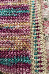 Close up of crochet afghan in self-striping yarn. The border is worked in cream and stef-striping yarn. thumbnail