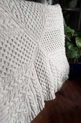 Full view of knit baby blanket, with all over cables, knit in a cool neutral cream color. thumbnail