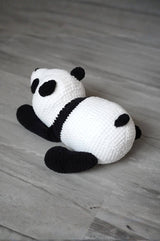 Back view of stuffed panda cub laying on its belly, showing its tiny black tail. thumbnail