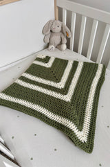 Crochet baby blanked folded into square, laid on crib mattress. A stuffed bunny sits nearby. thumbnail