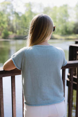 Back view of knit t-shirt. Woman wearing it is leaning against a deck railing, looking over water. thumbnail