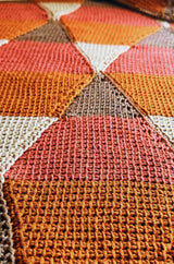 Extreme close up of Tunisian crochet texture on diamond motif, in rust, canyon red, taupe, and beige. thumbnail