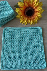 Close up of aqua cloth laid open, with a sunflower bloom at top of frame. thumbnail