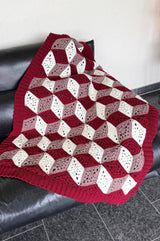 Crochet afghan draped over black leather couch. thumbnail