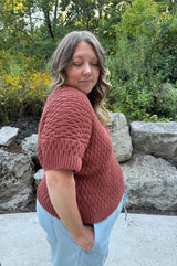 Side view of crochet tee, showing shoulder seam and short sleeve. Tee has an all-over textured pattern. thumbnail