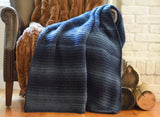 Crochet blanket shown in smaller size draped over arm of leather armchair thumbnail