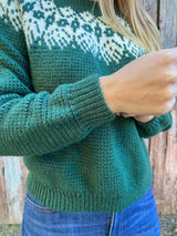Close up of cuff on long sleeve of green sweater. thumbnail