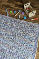 flat lay of crochet blanket with kids toys scattered slightly slanted downward thumbnail
