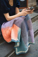closeup of a crochet blanket draped over woman's lap thumbnail