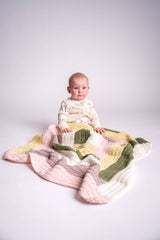 baby with multicolor log cabin crochet blanket in front of white background thumbnail