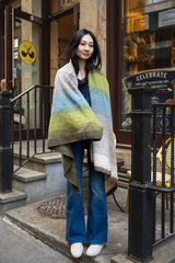 woman standing in front of store wrapped in colorful knit blanket thumbnail