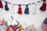 red white and blue yarn and bead garland hung over a patriotic table display thumbnail