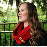 red crocheted tulip stitch cowl with brown wooden buttons worn by a smiling woman outdoors thumbnail
