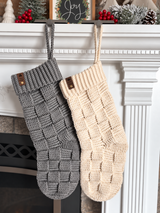 handmade gray and beige crochet Christmas stockings with basketweave texture hanging on a white mantel with a fireplace thumbnail
