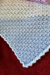 close-up of handmade pastel C2C Suzette stitch baby blanket draped over a red chair thumbnail