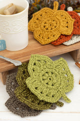 crocheted leaf-shaped coasters in autumn colors on a wooden board next to a cup of tea thumbnail