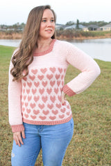 woman wearing a light pink crocheted heart motif sweater outdoors thumbnail