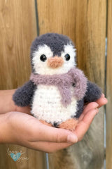 stuffed penguin toy in front of fence thumbnail