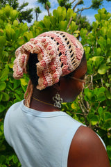 pink and cream yarn hat with floral patterns and textured details worn over the head thumbnail