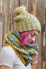 woman wearing a teal alpine stitch crochet beanie with a faux fur pom pom and matching cowl outdoors thumbnail