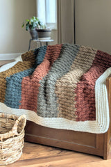 striped crochet blanket with white border laid over bench thumbnail