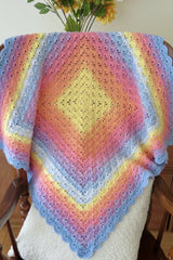 Shell stitch crochet blanket draped over chair thumbnail