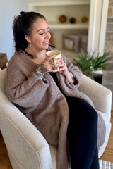 woman sitting with coffee in chair wearing cardigan thumbnail