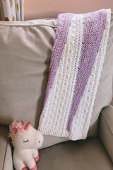 Purple and white baby blanket draped on a chair thumbnail