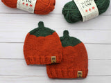 two knitted orange pumpkin beanies with orange and green yarn skeins thumbnail