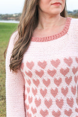 woman wearing a light pink crocheted heart motif sweater outdoors thumbnail