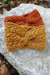 rust orange and mustard yellow crocheted ear warmer headbands stacked on a rock thumbnail