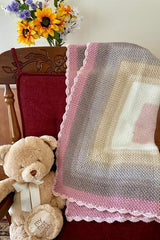 handmade pink, white, and tan moss stitch baby blanket with a scalloped edge on a wooden chair thumbnail