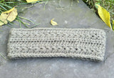 textured star stitch crochet headband laid flat on a grey stone surface surrounded by fallen autumn leaves thumbnail