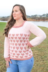 woman wearing a light pink crocheted heart motif sweater outdoors thumbnail