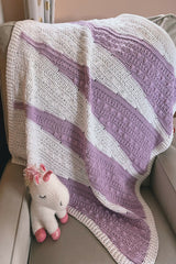 Purple and white baby blanket draped on a chair thumbnail