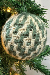 handmade argyle mosaic crochet Christmas ornament hanging on a pine tree with fairy lights thumbnail