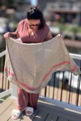 Woman holding tan and pink shawl on a dock thumbnail